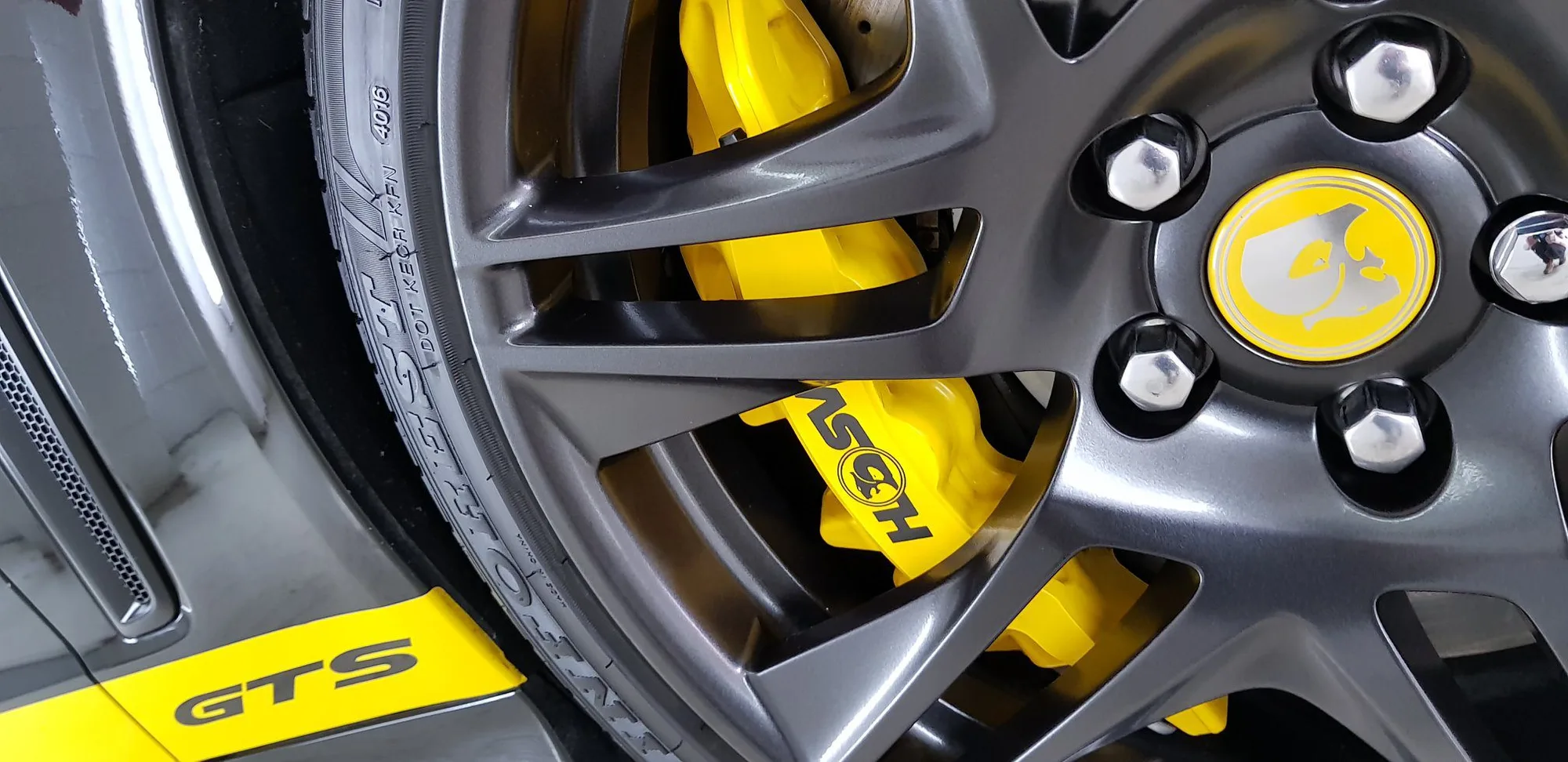 Yellow Porsche GTS brake caliper behind a coated alloy wheel after wheel and caliper coating