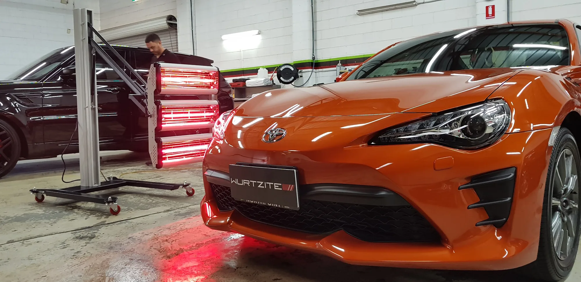 Orange Toyota 86 detailed and parked under the Wurtzite sign in the Ceramicar workshop